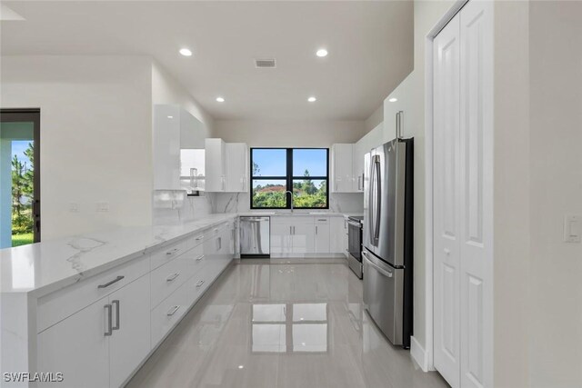 3115 41st St SW, Lehigh Acres, FL 33976 - kitchen with stainless steel appliances, a peninsula, white cabinets, recessed lighting, and light stone counters
