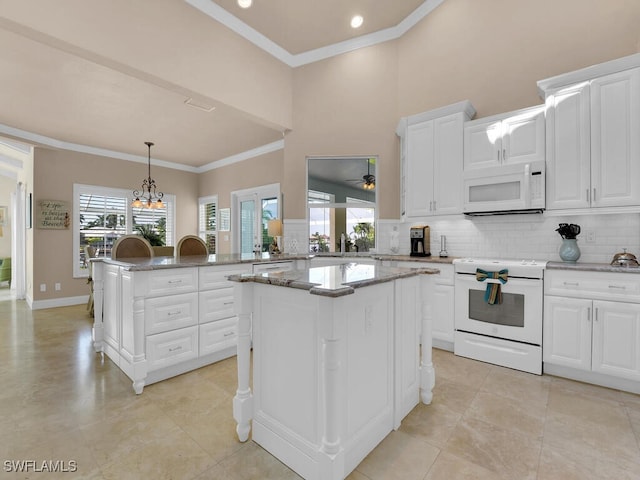 2546 SW 45th St, Cape Coral, FL 33914 - kitchen with white appliances, ornamental molding, a kitchen island, decorative backsplash, and a chandelier
