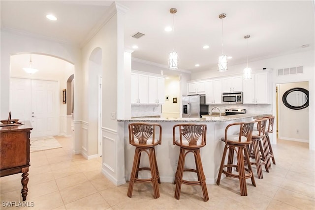 3260 Magnolia Landing Ln, North Fort Myers, FL 33917 - kitchen featuring appliances with stainless steel finishes, arched walkways, crown molding, light tile patterned floors, and a breakfast bar area