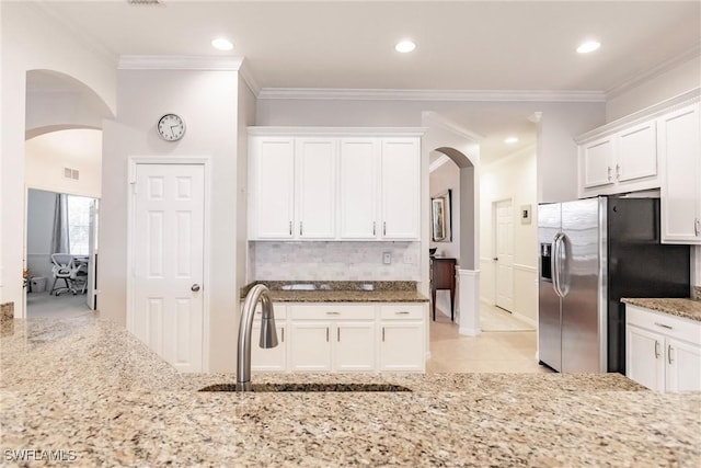 3260 Magnolia Landing Ln, North Fort Myers, FL 33917 - kitchen featuring arched walkways, stainless steel fridge, light stone countertops, white cabinets, and crown molding