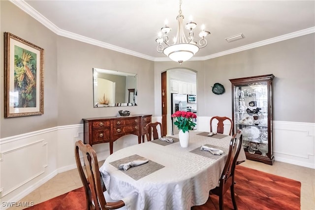 3260 Magnolia Landing Ln, North Fort Myers, FL 33917 - dining room with a chandelier, ornamental molding, light tile patterned floors, arched walkways, and a wainscoted wall
