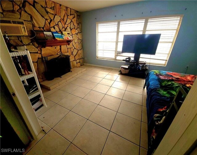 340 Inwood Ave S, Lehigh Acres, FL 33936 - tiled bedroom featuring a stone fireplace and an AC wall unit
