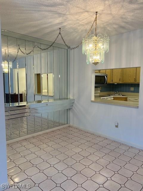 9950 Sailview Ct Unit 12, Fort Myers, FL 33905 - kitchen featuring stainless steel microwave, a chandelier, stove, tile patterned floors, and a textured ceiling