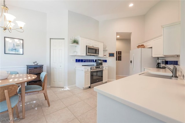 6325 Wilshire Pines Cir Unit 3, Naples, FL 34109 - kitchen featuring stainless steel appliances, high vaulted ceiling, open shelves, a chandelier, and white cabinets