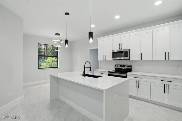 1002 E 17th St, Lehigh Acres, FL 33972 - kitchen with stainless steel appliances, recessed lighting, a center island with sink, white cabinets, and decorative light fixtures