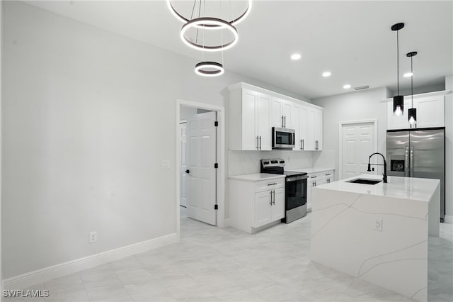 1002 E 17th St, Lehigh Acres, FL 33972 - kitchen with appliances with stainless steel finishes, white cabinetry, decorative light fixtures, an island with sink, and recessed lighting