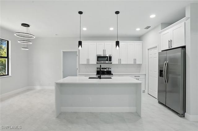 1002 E 17th St, Lehigh Acres, FL 33972 - kitchen featuring stainless steel appliances, light countertops, white cabinets, an island with sink, and pendant lighting