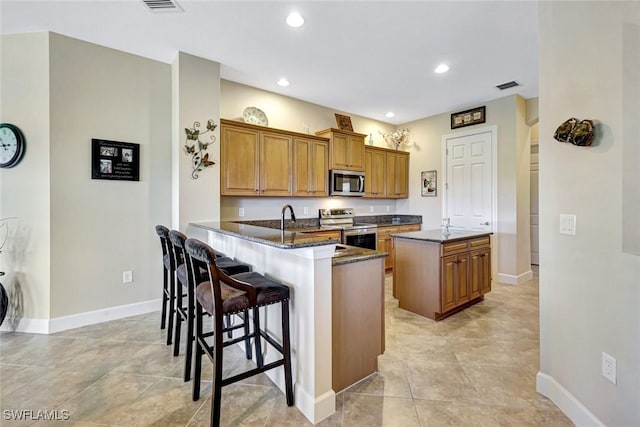 9693 Cobalt Cove Cir, Naples, FL 34120 - kitchen with stainless steel appliances, brown cabinetry, a kitchen bar, a center island, and recessed lighting