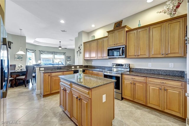 9693 Cobalt Cove Cir, Naples, FL 34120 - kitchen with stainless steel appliances, a peninsula, brown cabinets, a kitchen island, and recessed lighting