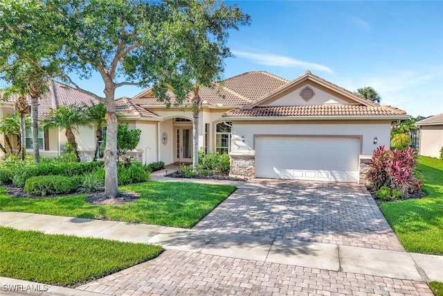 9693 Cobalt Cove Cir, Naples, FL 34120 - mediterranean / spanish home featuring stucco siding, an attached garage, decorative driveway, and a front yard