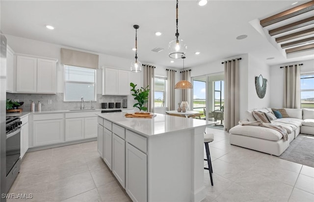 604 Oasis Lake Pl, Lehigh Acres, FL 33936 - kitchen with open floor plan, stainless steel range oven, backsplash, a kitchen island, and light tile patterned flooring