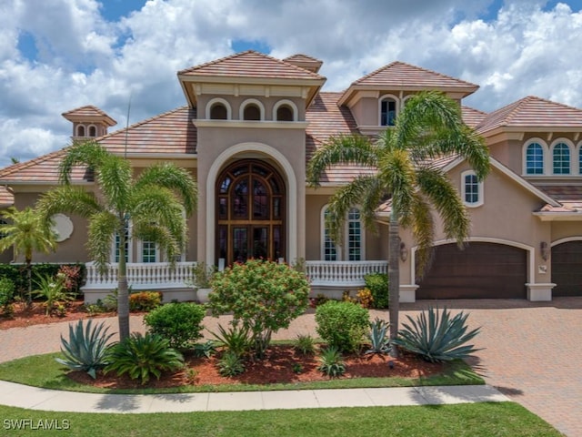 504 Tigertail Ct, Marco Island, FL 34145 - mediterranean / spanish home featuring stucco siding, a garage, decorative driveway, covered porch, and a tile roof