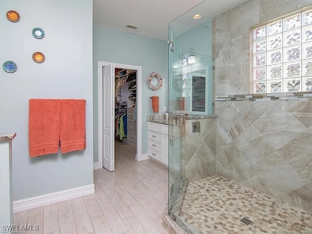 27329 Jolly Roger Ln, Bonita Springs, FL 34135 - bathroom featuring a shower stall, a walk in closet, wood finished floors, and vanity
