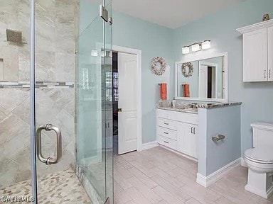 27329 Jolly Roger Ln, Bonita Springs, FL 34135 - bathroom featuring vanity, a shower stall, and wood finished floors