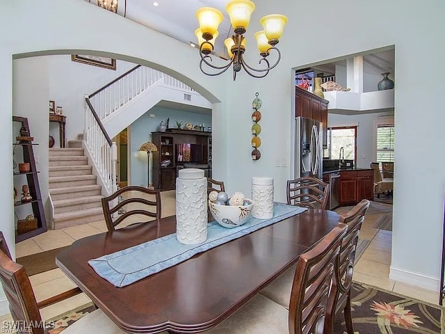 27329 Jolly Roger Ln, Bonita Springs, FL 34135 - dining area featuring a chandelier, arched walkways, light tile patterned floors, stairs, and a high ceiling
