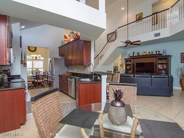 27329 Jolly Roger Ln, Bonita Springs, FL 34135 - kitchen featuring a towering ceiling, dark countertops, light tile patterned floors, appliances with stainless steel finishes, and a chandelier