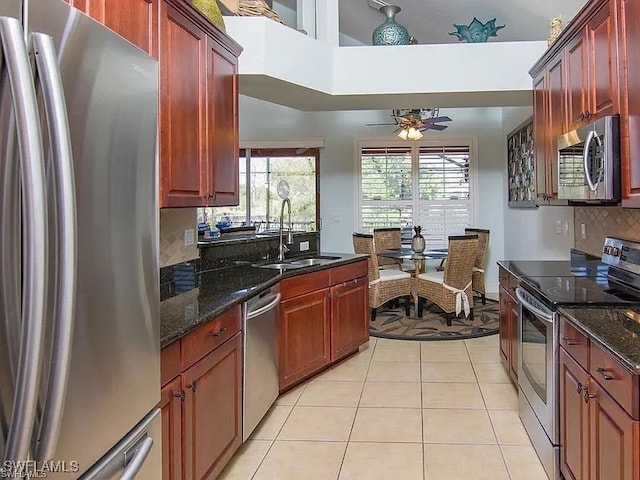 27329 Jolly Roger Ln, Bonita Springs, FL 34135 - kitchen featuring appliances with stainless steel finishes, decorative backsplash, light tile patterned floors, a ceiling fan, and dark stone counters