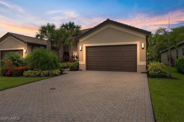 28646 Lobos Cir, Bonita Springs, FL 34135 - ranch-style house with stucco siding, decorative driveway, a front lawn, and an attached garage