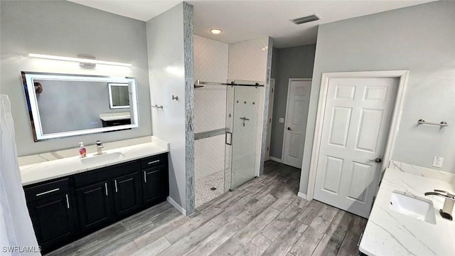 3940 Ruxton Rd, Naples, FL 34116 - bathroom featuring two vanities, a stall shower, and wood finished floors