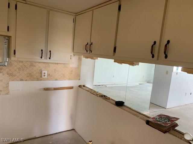 11060 Caravel Cir Unit 104, Fort Myers, FL 33908 - kitchen featuring light countertops, decorative backsplash, unfinished concrete flooring, and cream cabinetry