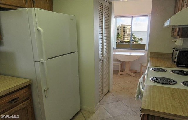 4265 Bay Beach Ln Unit 524, Fort Myers Beach, FL 33931 - kitchen featuring freestanding refrigerator, under cabinet range hood, light tile patterned floors, and light countertops