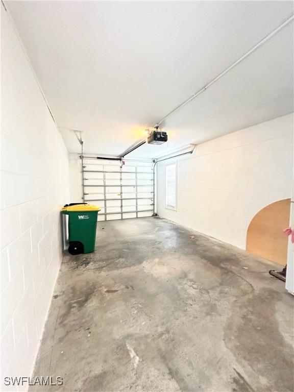 7066 Barrington Cir Unit 201, Naples, FL 34108 - garage featuring a garage door opener and concrete block wall
