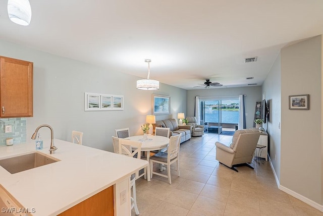 20050 Fiddlewood Ave, North Fort Myers, FL 33917 - kitchen featuring light countertops, light tile patterned floors, a ceiling fan, open floor plan, and brown cabinetry