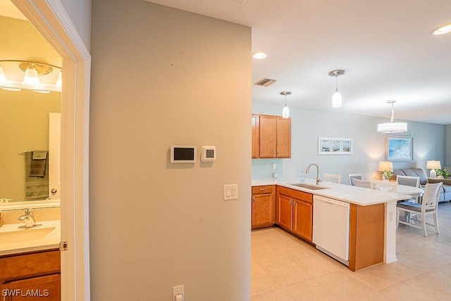 20050 Fiddlewood Ave, North Fort Myers, FL 33917 - kitchen featuring white dishwasher, a peninsula, brown cabinets, light countertops, and light tile patterned floors