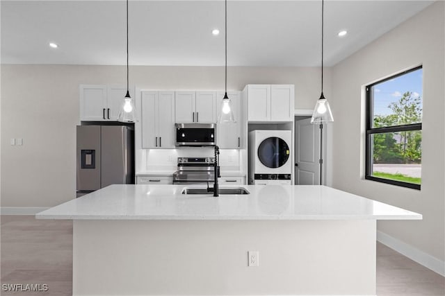 1201 E 7th St, Lehigh Acres, FL 33972 - kitchen with stainless steel appliances, stacked washer / dryer, a center island with sink, light wood-type flooring, and recessed lighting