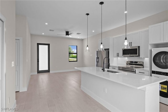 1201 E 7th St, Lehigh Acres, FL 33972 - kitchen featuring appliances with stainless steel finishes, stacked washer / dryer, ceiling fan, light countertops, and a center island with sink