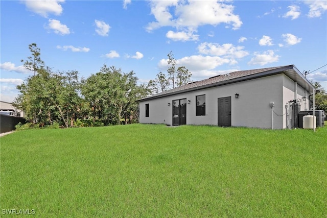 1201 E 7th St, Lehigh Acres, FL 33972 - rear view of property with stucco siding and a lawn