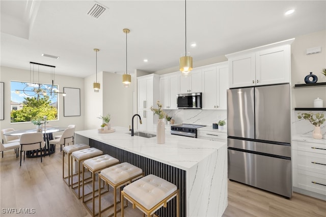 3008 20th St SW, Lehigh Acres, FL 33976 - kitchen with appliances with stainless steel finishes, white cabinetry, decorative backsplash, light wood-type flooring, and light stone counters