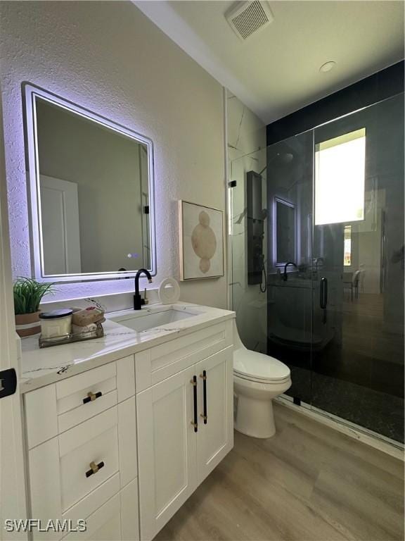 3008 20th St SW, Lehigh Acres, FL 33976 - full bath with vanity, wood finished floors, a stall shower, and a textured wall