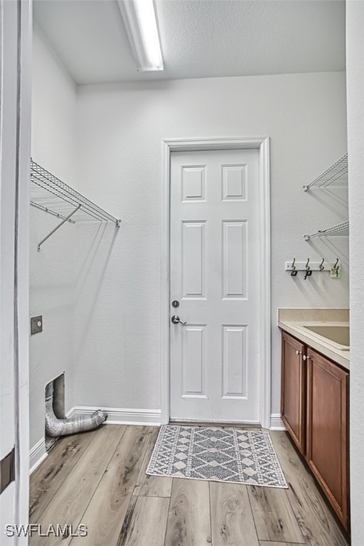 13461 Sabal Pointe Dr, Fort Myers, FL 33905 - laundry area with cabinet space, light wood-style flooring, and electric dryer hookup