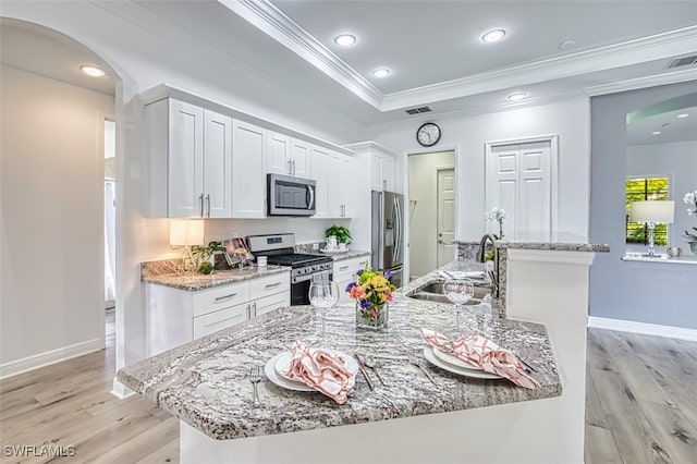 13461 Sabal Pointe Dr, Fort Myers, FL 33905 - kitchen with appliances with stainless steel finishes, arched walkways, ornamental molding, light wood-type flooring, and white cabinets