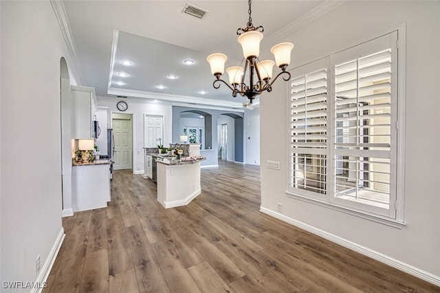 13461 Sabal Pointe Dr, Fort Myers, FL 33905 - kitchen with arched walkways, ornamental molding, white cabinets, a chandelier, and dark wood-style floors