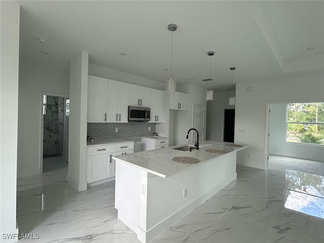 1402 Henry Ave, Lehigh Acres, FL 33972 - kitchen with stainless steel microwave, light marble finish flooring, white cabinets, and tasteful backsplash