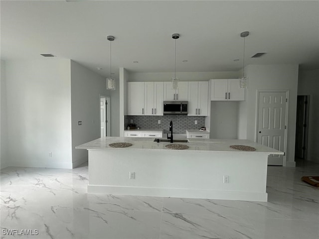 1402 Henry Ave, Lehigh Acres, FL 33972 - kitchen featuring stainless steel microwave, white cabinetry, a large island, and light marble finish flooring