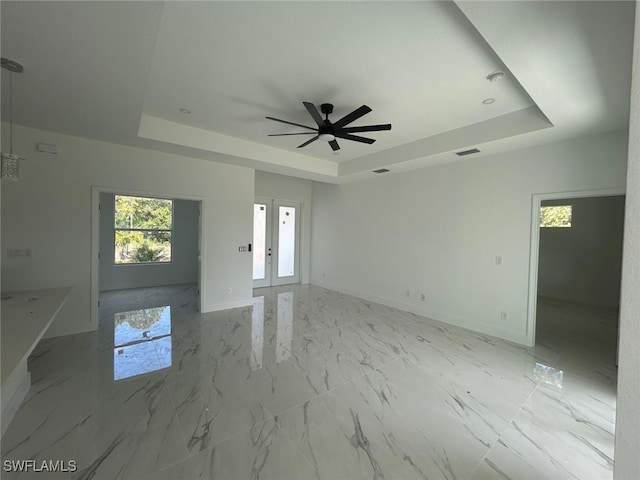 1402 Henry Ave, Lehigh Acres, FL 33972 - unfurnished living room featuring a raised ceiling, ceiling fan, light marble finish flooring, and french doors