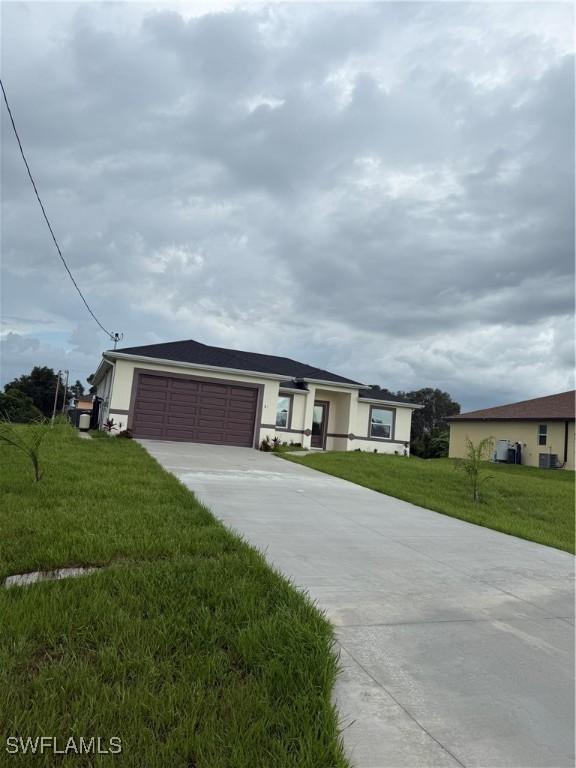 311 Rand Ave, Lehigh Acres, FL 33974 - ranch-style home with concrete driveway, a garage, a front lawn, and stucco siding