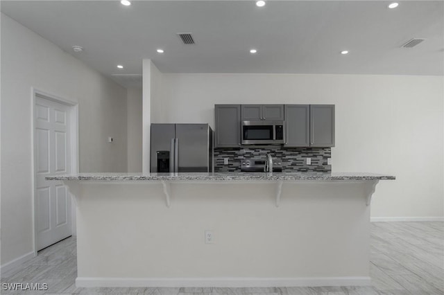 311 Rand Ave, Lehigh Acres, FL 33974 - kitchen featuring stainless steel appliances, gray cabinets, decorative backsplash, a breakfast bar area, and recessed lighting