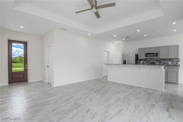 311 Rand Ave, Lehigh Acres, FL 33974 - unfurnished living room with a tray ceiling, recessed lighting, and ceiling fan