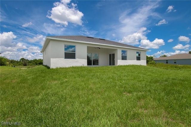 311 Rand Ave, Lehigh Acres, FL 33974 - rear view of house featuring stucco siding and a yard