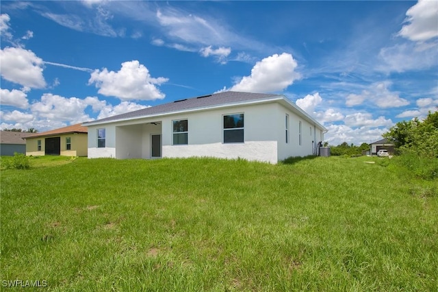 311 Rand Ave, Lehigh Acres, FL 33974 - back of house with stucco siding, a lawn, and a ceiling fan