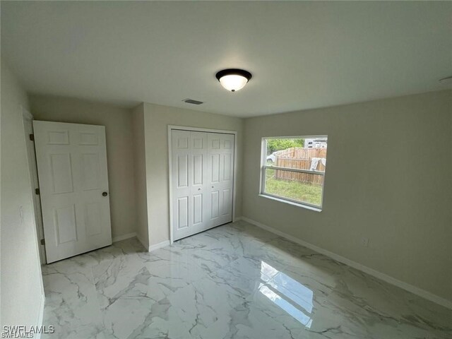 1112/1114 Ivan Ave S, Lehigh Acres, FL 33973 - unfurnished bedroom with marble look tiles and a closet