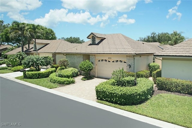 922 Turtle Ct Unit 21-21, Naples, FL 34108 - view of front facade with a garage, a tiled roof, driveway, and stucco siding
