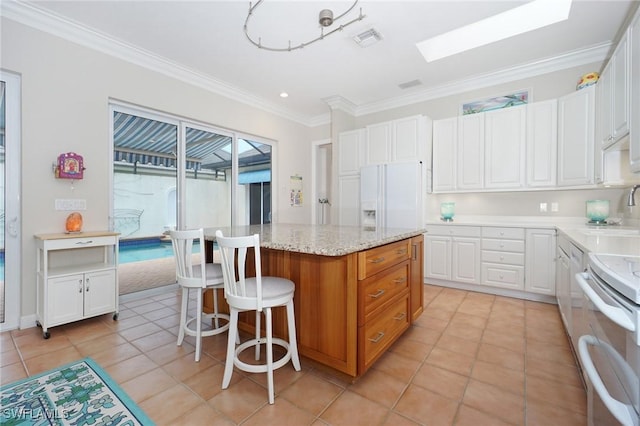 922 Turtle Ct Unit 21-21, Naples, FL 34108 - kitchen with a kitchen island, white appliances, crown molding, white cabinets, and a kitchen bar