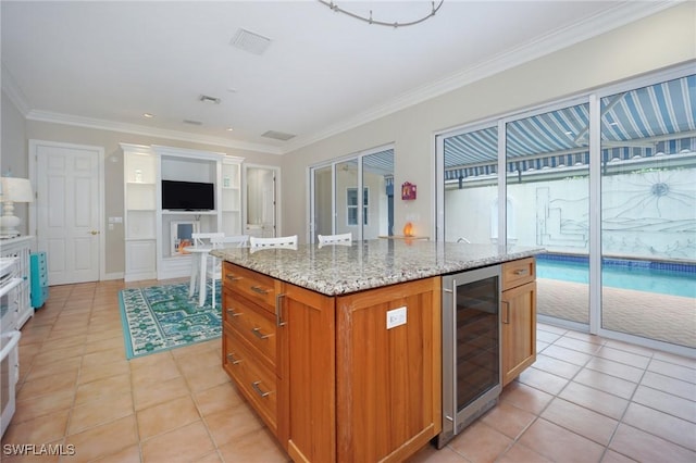 922 Turtle Ct Unit 21-21, Naples, FL 34108 - kitchen with wine cooler, light tile patterned flooring, ornamental molding, brown cabinetry, and a center island with sink