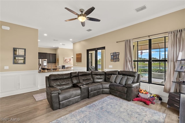 5158 Roma St, Ave Maria, FL 34142 - living area featuring a ceiling fan, light wood finished floors, ornamental molding, wainscoting, and a decorative wall