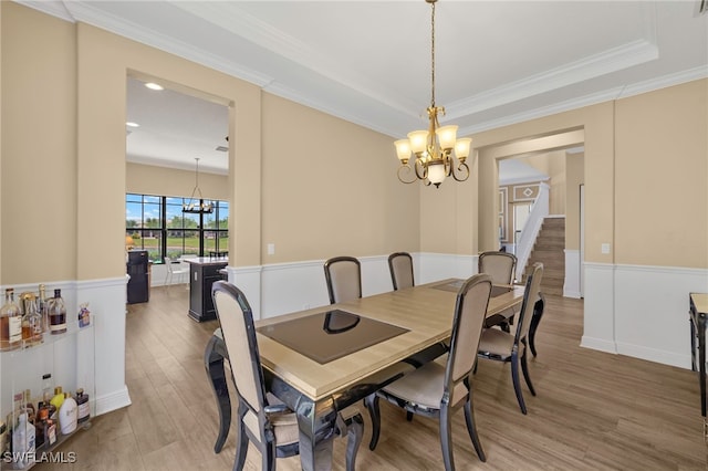 5158 Roma St, Ave Maria, FL 34142 - dining space with a chandelier, light wood-style flooring, ornamental molding, wainscoting, and stairway